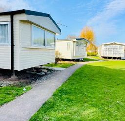 two holiday caravans on a grassy area with a walkway at Butlins Minehead - Holiday Accommodation 13288 Minehead
