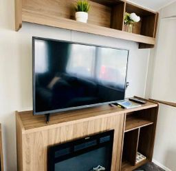 a television on a wooden entertainment unit with shelves at Butlins Minehead - Holiday Accommodation 13288 in Minehead