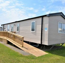 a mobile home with a wooden ramp and grassy area at Perran Sands - Holiday Accommodation 15554, Perranporth