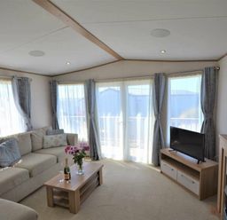 a living room with a sectional sofa, coffee table, television, and large windows at Perran Sands - Holiday Accommodation 15598 in Perranporth