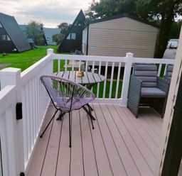 a patio with a table and chairs overlooking green grass at Hafan y Mor Haven - Holiday Accommodation 15817 in Pwllheli
