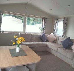 a seating area with a corner sofa and a table at Hafan y Mor Haven - Holiday Accommodation 15817 in Pwllheli