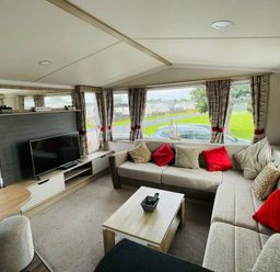 a living room with a sectional sofa, TV, and windows at Unity Holiday Resort - Holiday Accommodation 15970 Brean Sands