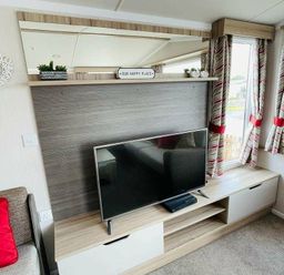 a living room with a television on a cabinet and curtains at Unity Holiday Resort - Holiday Accommodation 15970, Brean Sands