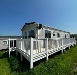 a mobile home with a deck and white railings at Newquay Bay Resort - Holiday Accommodation 15978 Newquay