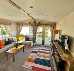 a living room with a sofa, a coffee table, and a television at Newquay Bay Resort - Holiday Accommodation 15978 in Newquay