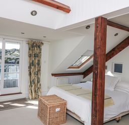 A bedroom with a bed and balcony window at Fastnet at Nonsuch House in Kingswear, Devon