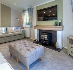 a living room with a sofa, television, a fireplace, and an ottoman at Kelling Heath Holiday Park - Holiday Accommodation 16221, Holt