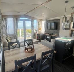 A living room with a sofa, dining area, and kitchen at Hafan y Mor Haven - Holiday Accommodation 16251, Pwllheli