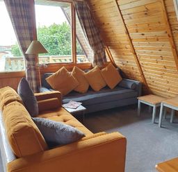 a seating area with two sofas and wooden tables at Hafan y Mor Haven - Holiday Accommodation 16279, Pwllheli