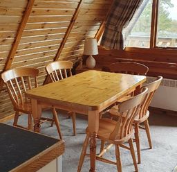 a wooden dining table with four chairs in an attic room at Hafan y Mor Haven - Holiday Accommodation 16279, Pwllheli