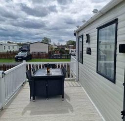 a table and chairs on a deck with a view of mobile homes at Unity Holiday Resort - Holiday Accommodation 16507, Brean, Somerset, United Kingdom