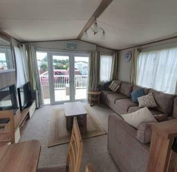 a living room with a sofa, coffee table, and large windows at Unity Holiday Resort - Holiday Accommodation 16507, Brean, Somerset, United Kingdom