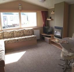 a living room with a sofa, TV unit, and dining table at Butlins Minehead - Holiday Accommodation 1700, Minehead