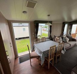 a dining area with a table and chairs in a mobile home at Hafan y Mor Haven - Holiday Accommodation 17436, Pwllheli