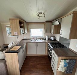 a kitchen with wooden cabinets and a stove at Hafan y Mor Haven - Holiday Accommodation 17436 Pwllheli