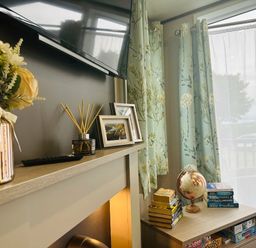 a living room with a TV, decorative flowers, curtains, and a globe at Ashbourne Heights Holiday Park - Holiday Accommodation 18103, Ashbourne