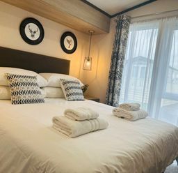 a bedroom with a bed, pillows, rolled towels, and framed animal pictures at Ashbourne Heights Holiday Park - Holiday Accommodation 18103, Ashbourne