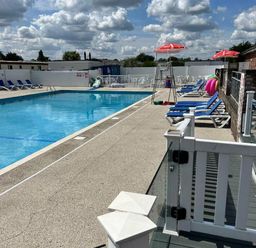 a swimming pool with lounge chairs and umbrellas at Breydon Water Holiday Park - Holiday Accommodation 18490 Great Yarmouth