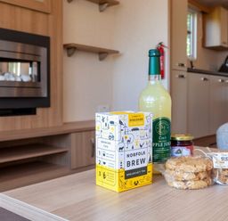 a wooden table with tea, apple juice, jam, and cookies in a living area at Kelling Heath Holiday Park - Holiday Accommodation 18663, Holt