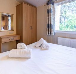 a bedroom with a bed and towels on it at Kelling Heath Holiday Park - Holiday Accommodation 18663, Holt