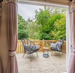 a deck with two chairs and a table overlooking greenery at Kelling Heath Holiday Park - Holiday Accommodation 18664, Holt
