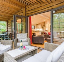 a seating area with wicker furniture and a view of a kitchen inside a cabin at Kelling Heath Holiday Park - Holiday Accommodation 18691 in Holt