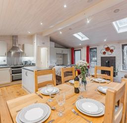 a dining area with a wooden table set for dinner in Kelling Heath Holiday Park - Holiday Accommodation 18691, Holt