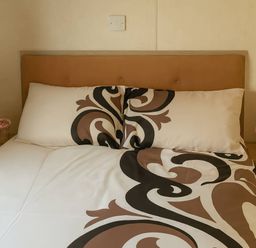 A bed with pillows and a nightstand at Golden Gate Holiday Centre - Holiday Accommodation 19059, Towyn