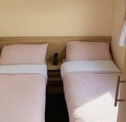 A bedroom with two beds and a bedside table at Golden Gate Holiday Centre - Holiday Accommodation 19059 in Towyn