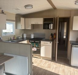 A kitchen with cabinets, sink, stove, microwave, and refrigerator at Southview Holiday Park - Holiday Accommodation 19123 Skegness