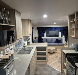A kitchen with appliances and a living area at Presthaven Beach Resort - Holiday Accommodation 19166, Prestatyn