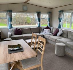 a living room with a sectional sofa and dining table at Butlins Skegness - Holiday Accommodation 19332 in Skegness