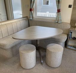 a dining area with a corner bench and round stools at Rockley Park - Holiday Accommodation 19386, Poole