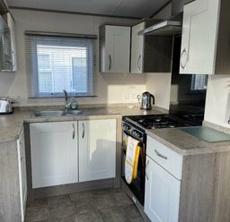 a kitchen with cabinets, a sink, a stove, and a window at Rockley Park - Holiday Accommodation 19386, Poole