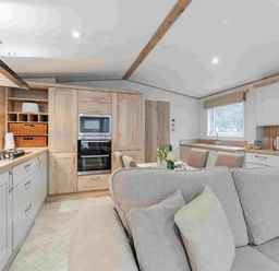 a kitchen with wooden cabinets and modern appliances at Kelling Heath Holiday Park - Holiday Accommodation 19669, Holt