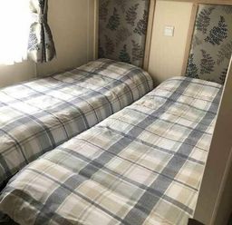 a bedroom with two single beds covered in checkered bedding at Pinewoods Holiday Park - Holiday Accommodation 19734 in Wells-Next-The-Sea