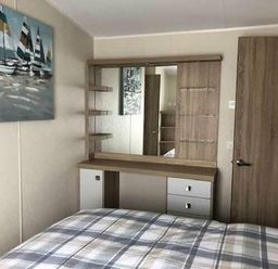 a bedroom with a bed and a dressing table with a mirror at Pinewoods Holiday Park - Holiday Accommodation 19734, Wells-Next-The-Sea