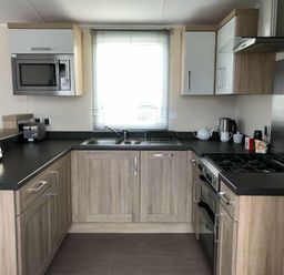 a kitchen featuring cabinets, a sink, a stove, and a microwave at Pinewoods Holiday Park - Holiday Accommodation 19734, Wells-Next-The-Sea