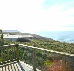 a view of the ocean and cliffs from a wooden deck at Perran Sands - Holiday Accommodation 19778 in Perranporth