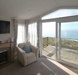 a living room with a fireplace and sea view at Perran Sands - Holiday Accommodation 19778 Perranporth