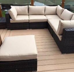 a sectional outdoor sofa with beige cushions on a wooden deck at Hafan y Mor Haven - Holiday Accommodation 19898 Pwllheli