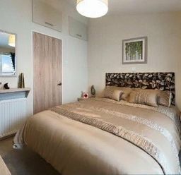 a bedroom with a double bed and decorative headboard at Hafan y Mor Haven - Holiday Accommodation 19898 in Pwllheli
