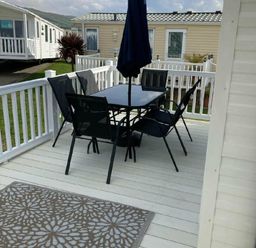 a outdoor dining set with a table and chairs on a wooden deck at Lyons Moelfre View - Holiday Accommodation 20226, Talybont