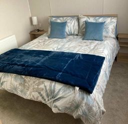 a bed with a patterned duvet and blue pillows at Lyons Moelfre View - Holiday Accommodation 20226, Talybont