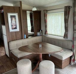 a dining area with a round table and corner seating at Sand Le Mere Holiday Village - Holiday Accommodation 20326 in Tunstall
