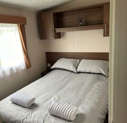 a bedroom with a double bed and shelves at Sand Le Mere Holiday Village - Holiday Accommodation 20326 in Tunstall