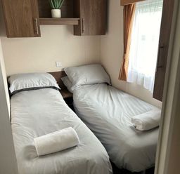 a small bedroom with two single beds and a window at Sand Le Mere Holiday Village - Holiday Accommodation 20326 in Tunstall