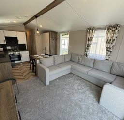 a lounge area with a gray sectional sofa and a small dining table at Hafan y Mor Haven - Holiday Accommodation 20481, Pwllheli