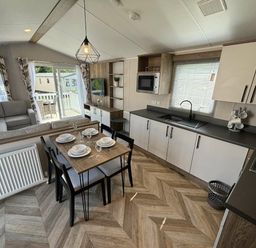 a dining area with a table set for four and a kitchen in Hafan y Mor Haven - Holiday Accommodation 20481 Pwllheli